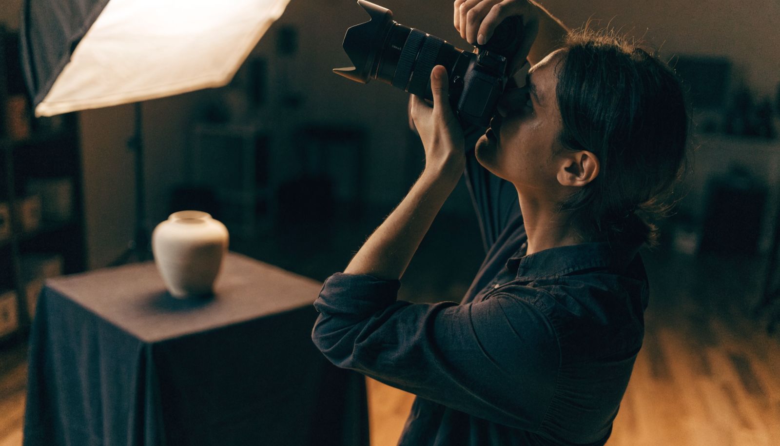An agency worker photographing a product on a small studio table under soft light