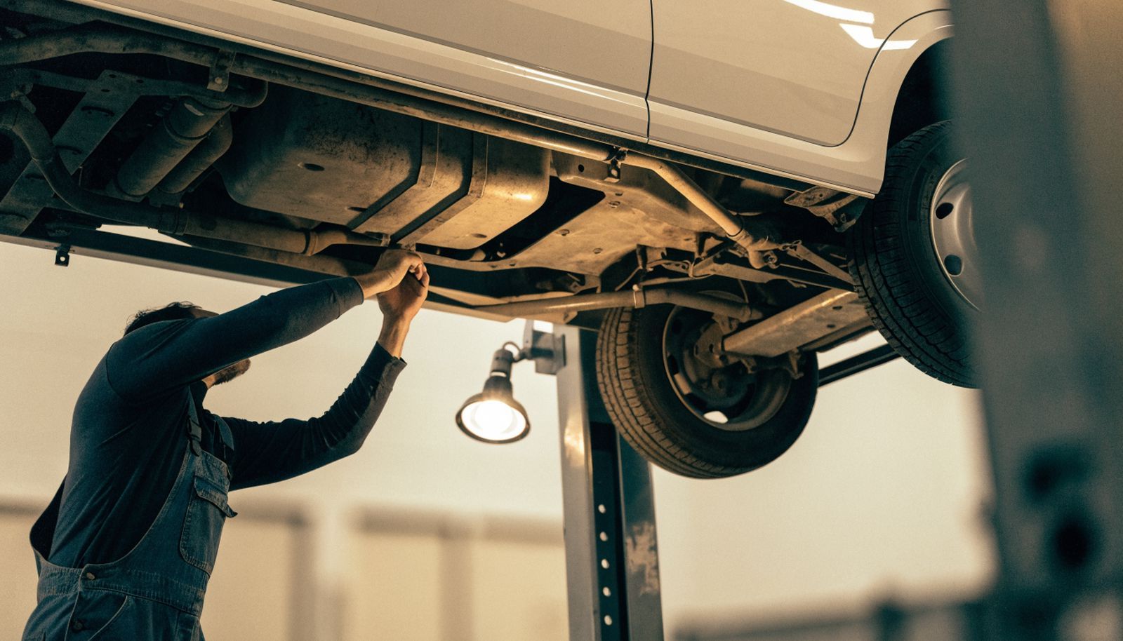 A mechanic working under a delivery van raised on a lift in a clean, well-lit workshop