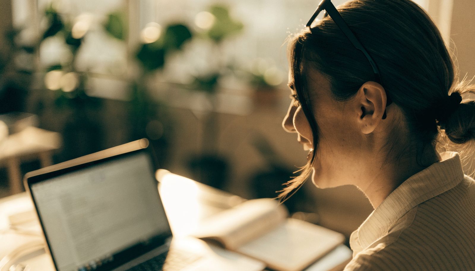 A recruiter in a video call at a bright desk, laptop open and headset on
