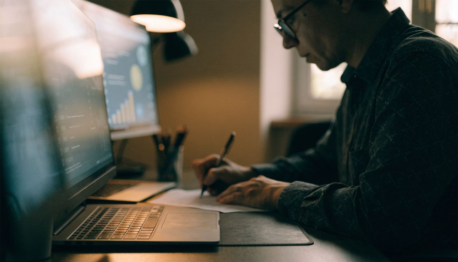 An SEO consultant at a desk, an analytics dashboard softly out of focus on the monitor behind them
